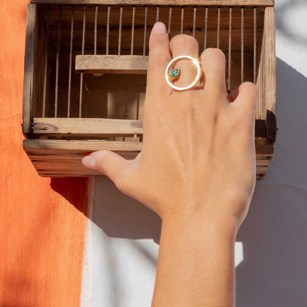 mano con un anillo de oro con piedra esmeralda en el centro