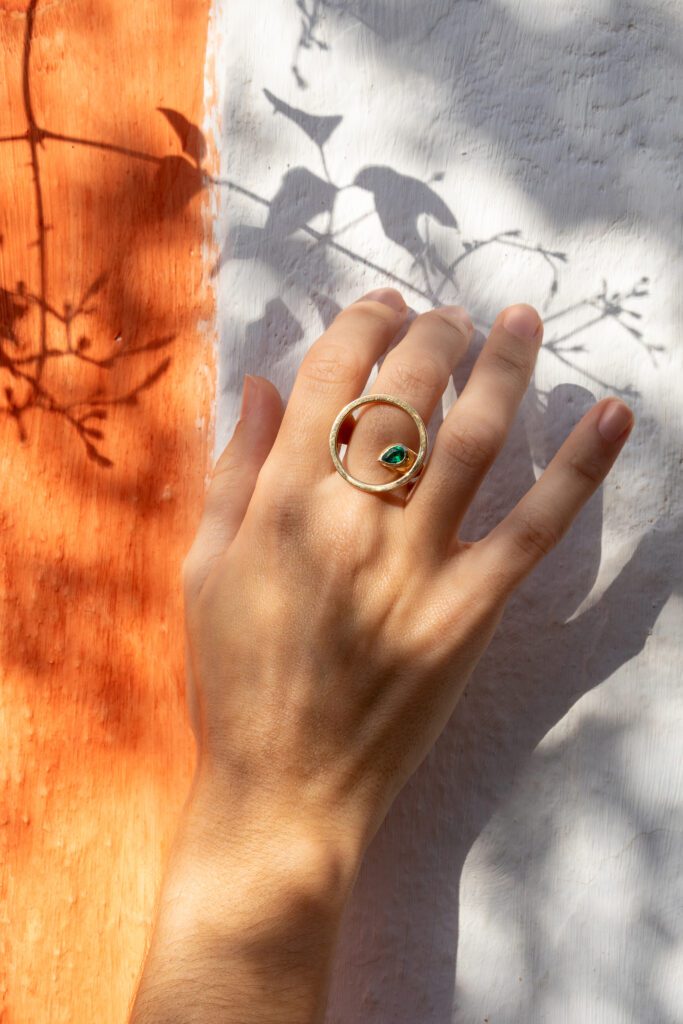 mano con un anillo de oro con piedra esmeralda en el centro