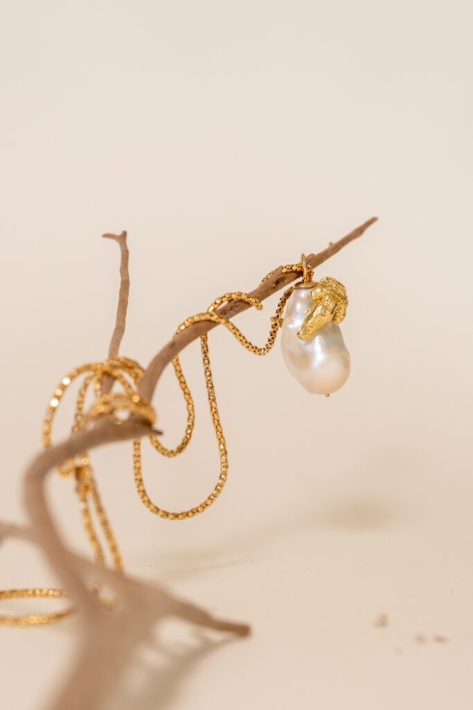 collar de perla y cocodrilo oro sobre rama seca